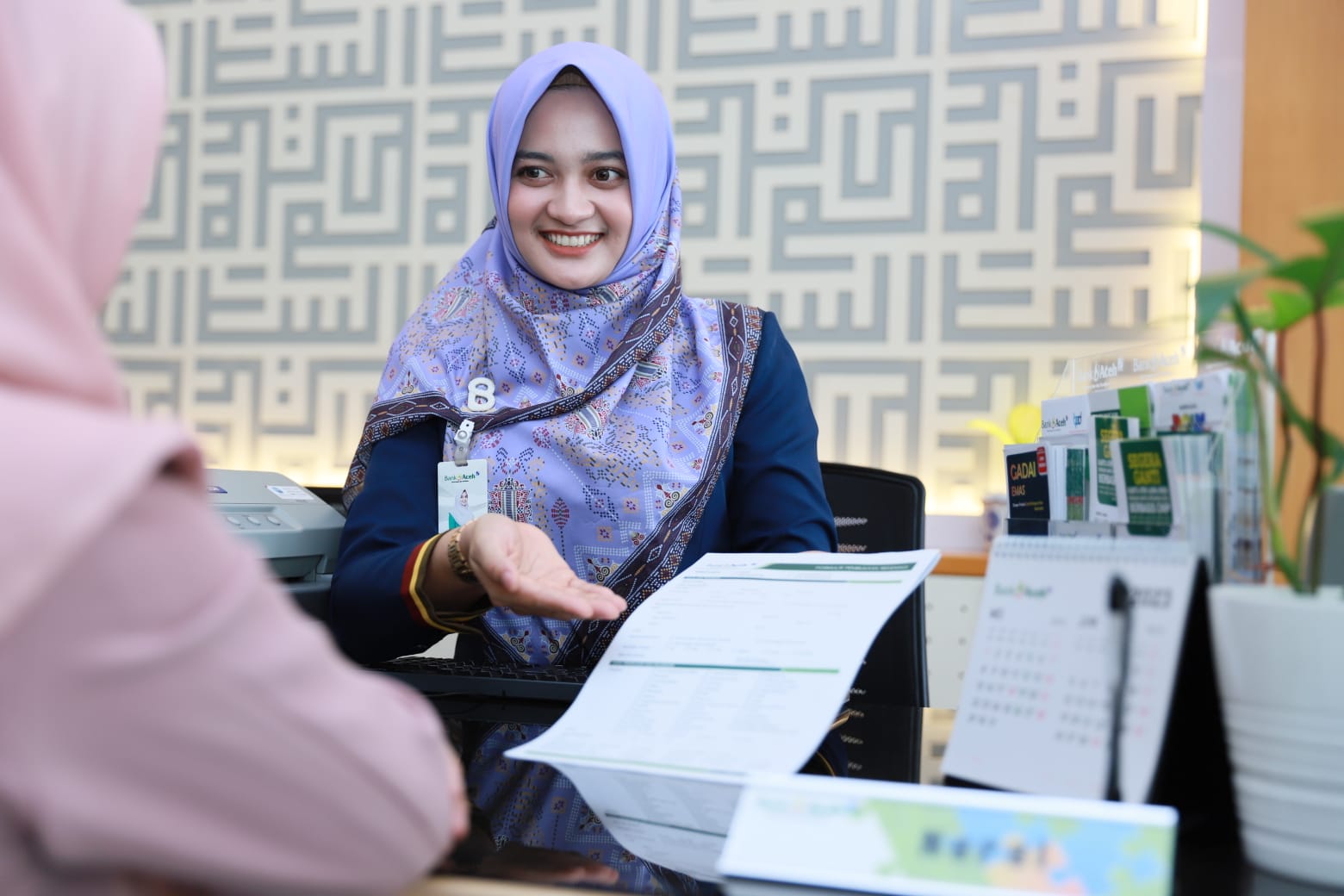 Karyawati Bank Aceh Syariah melayani nasabah di Kantor Bank Aceh Cabang Banda Aceh, Selasa (21/3)