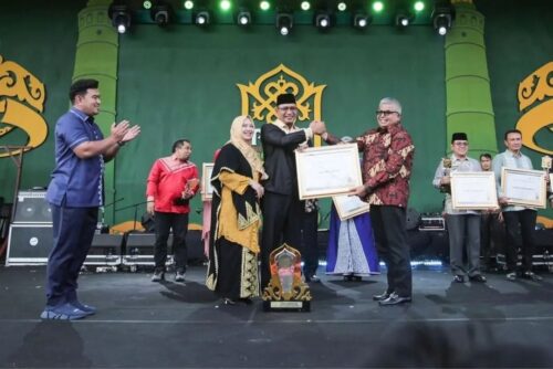 Sekda Aceh Bustami Hamzah menyerahkan Piala Juara Umum PKA-8 kepada Pj Bupati Aceh Selatan Cut Syazalisma saat penutupan PKA-8 di Taman Sulthanah Safiatuddin Banda Aceh, Ahad sore (12/11)