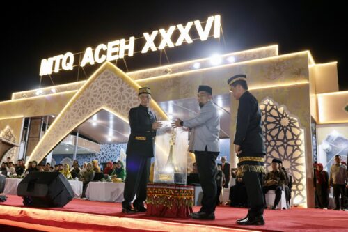 Pj Gubernur Aceh Achmad Marzuki menerima Piala Bergilir MTQ Aceh dari Pj Bupati Aceh Besar Muhammad Iswanto, selaku Juara Umum pada MTQ XXXV, pada pembukaan MTQ XXXVI Aceh, di Lapangan Pendopo Bupati Simeulue, Ahad malam (26/11)