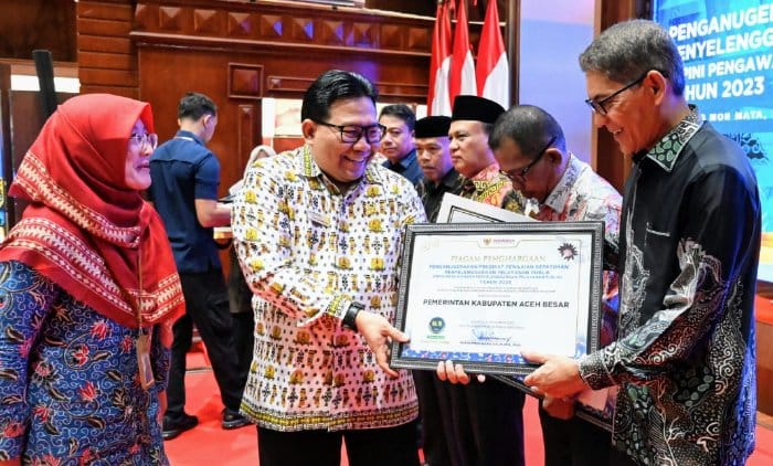 Pimpinan Ombudsman RI, Dadan S. Suharmawijaya menyerahkan Penghargaan dan Sertifikat Penganugerahan Predikat Penilaian Kepatuhan Penyelenggaraan Pelayanan Publik kepada Asisten III Pemkab Aceh Besar Jamaluddin, MM di Ajong Mon Mata, Banda Aceh, Kamis (25/1)