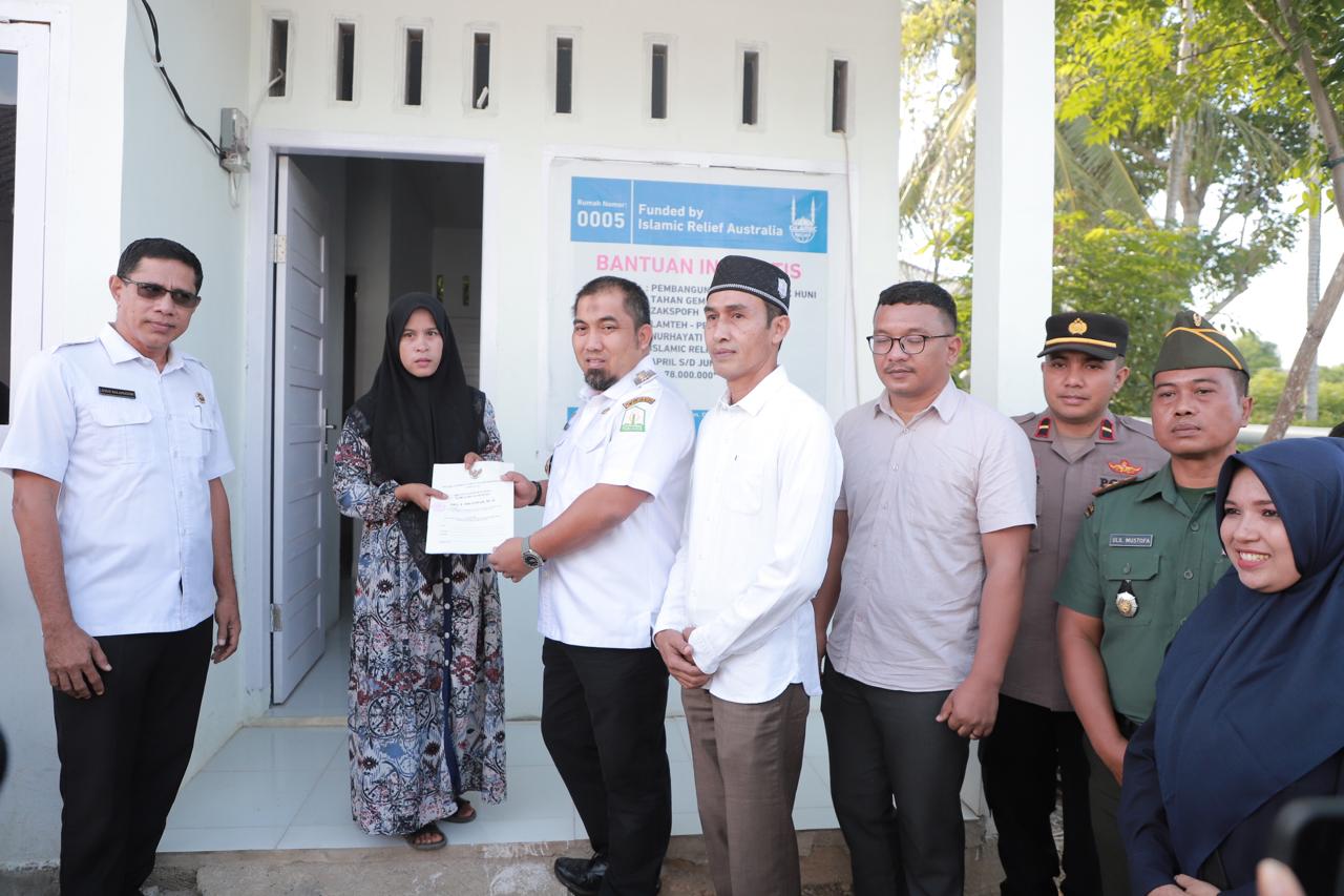 Pj Bupati Aceh Besar Muhammad Iswanto menyerahkan sertifikat rumah kepada Nurhayati salah satu penerima bantuan rumah layak huni bantuan dari Islamic Relief Indonesia dan Baitul Mal Aceh Besar di Gampong Lamteh Kecamatan Peukan Badan, Rabu (26/6). FOTO/MC ACEH BESAR