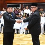 Pj Gubernur Aceh Bustami Hamzah menyerahkan SK perpanjangan jabatan tahun ketiga kepada Pj Bupati Aceh Besar, Muhammad Iswanto di Anjong Mon Mata, Banda Aceh, Ahad (14/7). (Foto: For Infoaceh.net)