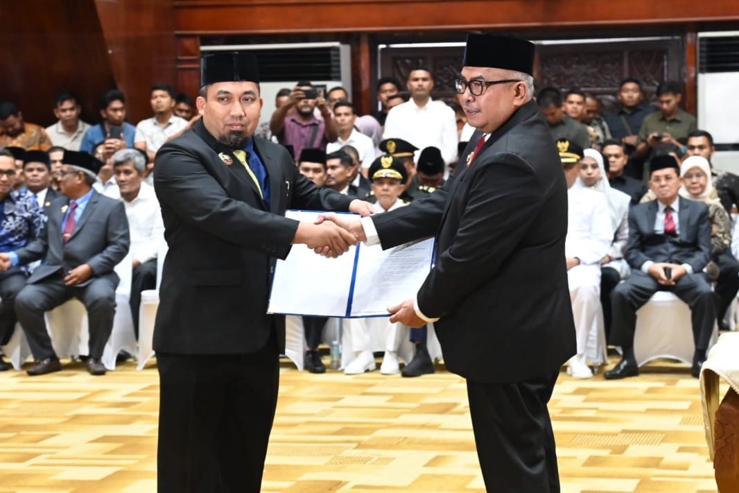 Pj Gubernur Aceh Bustami Hamzah menyerahkan SK perpanjangan jabatan tahun ketiga kepada Pj Bupati Aceh Besar, Muhammad Iswanto di Anjong Mon Mata, Banda Aceh, Ahad (14/7). (Foto: For Infoaceh.net)