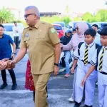 Pj Gubernur Aceh Bustami Hamzah bersama Bunda PAUD Aceh Mellani Subarni mengantar anak pada hari pertama sekolah ke SDIT Al Azhar Cairo Banda Aceh, Senin (15/7). Foto: Istimewa
