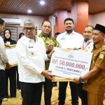 Pj Gubernur Aceh Bustami Hamzah menyerahkan penghargaan kepada Keuchik Gampong Bueng Sidom Kecamatan Blang Bintang, Aceh Besar, yang terpilih sebagai Gampong atau Desa Terbaik se-Aceh tahun 2024. (Foto: For Infoaceh.net)