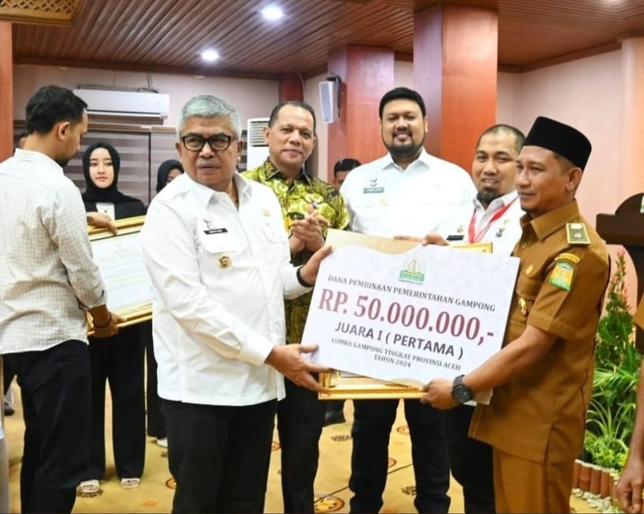 Pj Gubernur Aceh Bustami Hamzah menyerahkan penghargaan kepada Keuchik Gampong Bueng Sidom Kecamatan Blang Bintang, Aceh Besar, yang terpilih sebagai Gampong atau Desa Terbaik se-Aceh tahun 2024. (Foto: For Infoaceh.net)