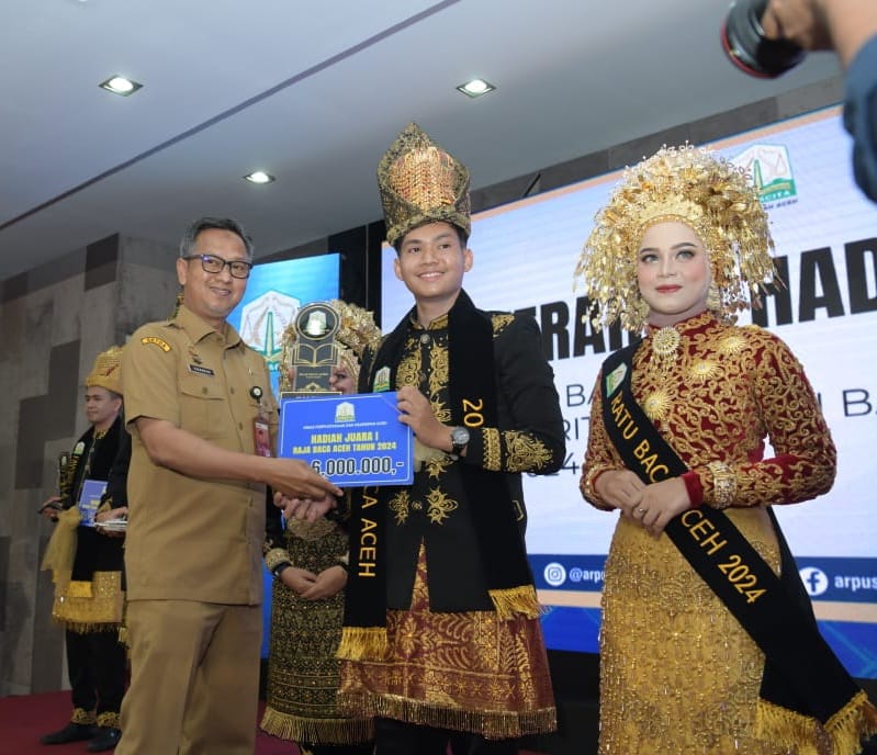 Asisten Administrasi Umum Sekda Aceh Dr Iskandar, menyerahkan hadiah sekaligus menobatkan Raja dan Ratu Baca Aceh 2024, di aula Perpustakaan Wilayah, Senin (5/8/2024). (Foto: For Infoaceh.net)