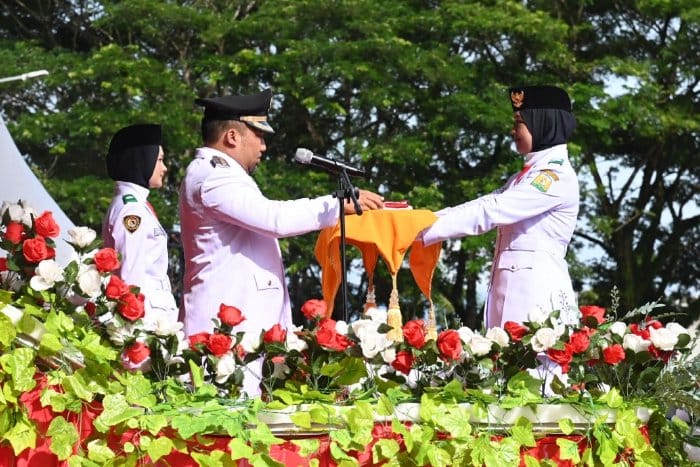 Pj Bupati Aceh Besar Muhammad Iswanto menyerahkan bendera merah putih kepada Paskibraka untuk dikibarkan pada upacara peringatan HUT ke-79 RI di Lapangan Bungong Jeumpa, Kota Jantho, Sabtu (17/8/2024). Foto: For Infoaceh.net