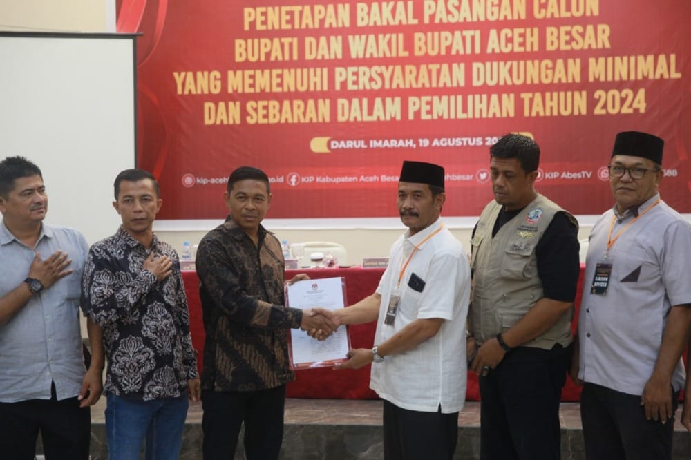Ketua KIP Aceh Besar T Khairun Salim, menyerahkan berkas syarat dan ketentuan Pilkada Aceh Besar kepada Syukri A. Jalil pada penetapan bakal pasangan calon Bupati/Wakil Bupati Aceh Besar yang memenuhi syarat di Orion Hall Kecamatan Darul Imarah, Aceh Besar, Senin (19/8). Foto: For Infoaceh.net