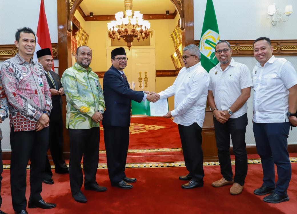 Pj Gubernur Aceh Bustami Hamzah menyerahkan SK pengangkatan Azwardi Abdullah sebagai Komisaris Utama Bank Aceh serta M Gaussyah sebagai Komisaris Independen Bank Aceh, Jum’at (16/8). (Foto: For Infoaceh.net)
