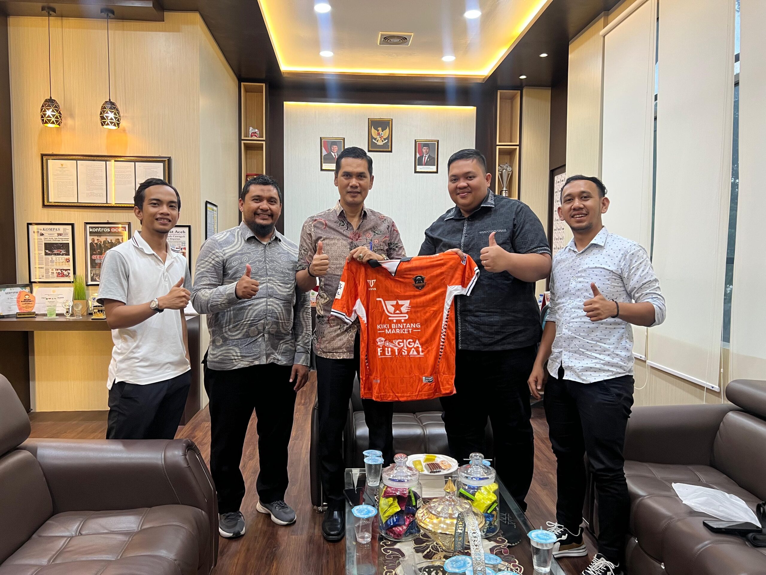 CEO Sadakata United, Ade Fadli Pratama Bintang menyerahkan jersey kepada Kadispora Aceh, Nasir Syamaun usai pertemuan di di ruang kerja Kadispora, Kamis (13/2). (Foto: For Infoaceh.net)