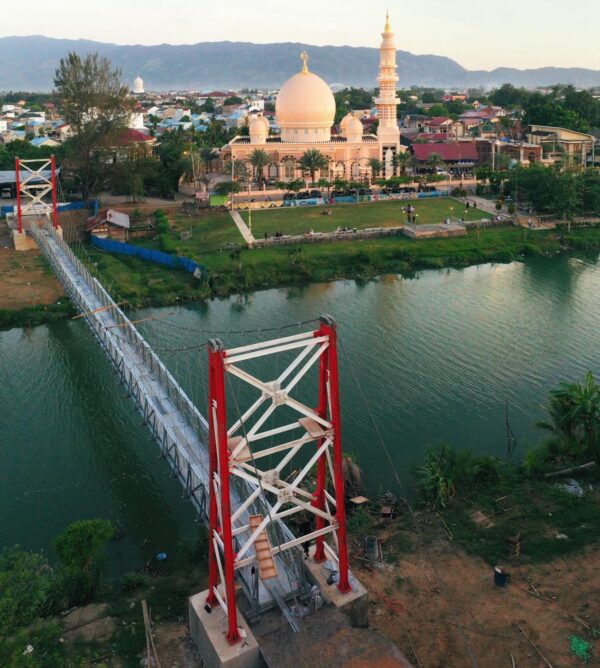 Jembatan gantung yang menghubungkan Gampong Lambhuk Kecamatan Ulee Kareng dan Gampong Lamseupeung Kecamatan Lueng Bata, Banda Aceh dengan latar belakang Masjid Haji Keuchik Leumiek. (Foto: Ist)