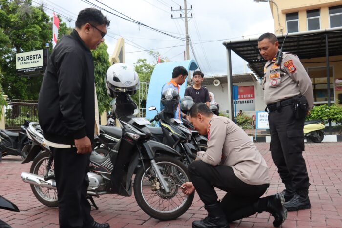 Kapolresta Banda Aceh Kombes Pol Joko Heri Purwono turun langsung membagikan sekaligus memasang kunci ganda sepeda motor berupa gembok kepada warga yang tengah mengurus SIM dan SKCK, Selasa (8/7). (Foto: Ist)
