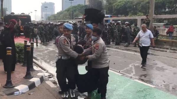 Seorang personel polisi dibopong rekan-rekannya setelah terluka akibat lemparan batu atau bambu saat mengamankan unjuk rasa di depan Gedung DPR/MPR, Jakarta, Senin (25/8/2025).