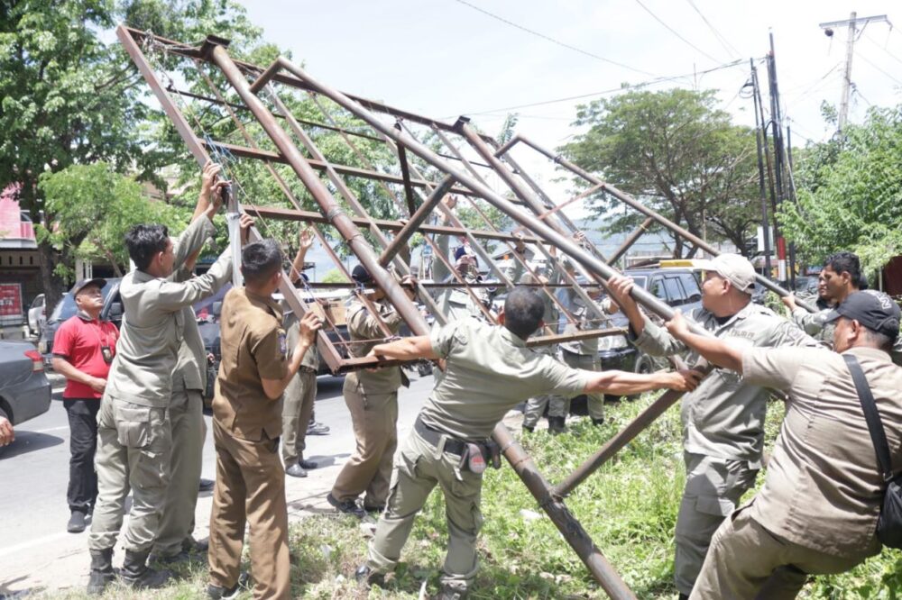 Petugas Satpol PP-WH Aceh Besar melakukan pembongkaran terhadap baliho yang melanggar aturan. (Foto: Ist)