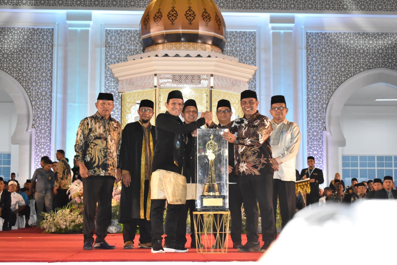 Wagub Aceh Fadhlullah menyerahkan piala bergilir juara umum MTQ ke-37 Provinsi Aceh kepada Bupati Aceh Besar Muharram Idris atau Syech Muharram saat menutup MTQ Aceh 2025 di Pidie Jaya, Jum'at malam (7/11). (Foto: Ist)