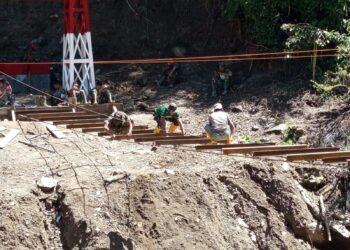 Prajurit TNI dan warga Desa Burni Bius saat bergotong royong memasang bantalan seling jembatan gantung. Infrastruktur ini diharapkan menjadi solusi permanen untuk memulihkan akses warga yang terputus akibat bencana. (Foto: Dok. Penerangan Kodim 0106/Aceh Tengah/Infoaceh)