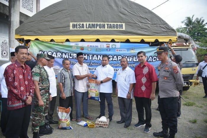 Pj Bupati Aceh Besar Muhammad Iswanto menyerahkan kebutuhan pokok secara simbolis kepada masyarakat saat pembukaan pasar murah yang digelar di halaman Meunasah Gampong Lampoh Tarom, Kemukiman Cot Keueng, Kecamatan Kuta Baro, Jum’at (3/3)