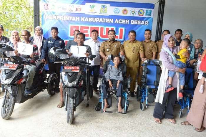 Pj Bupati Aceh Besar Muhammad Iswanto didampingi Kadis Sosial Aceh Besar Bahrul Jamil Anggota DPRK Aceh Besar Mustafa Ishak dan Camat Ingin Jaya, Al Mubarak Akbar foto bersama dengan penerima bantuan motor tiga roda dan kursi roda untuk disabilitas, di gudang Dinsos Aceh Besar, Gampong Pasie Garot, Ingin Jaya, Aceh Besar, Selasa (27/6)