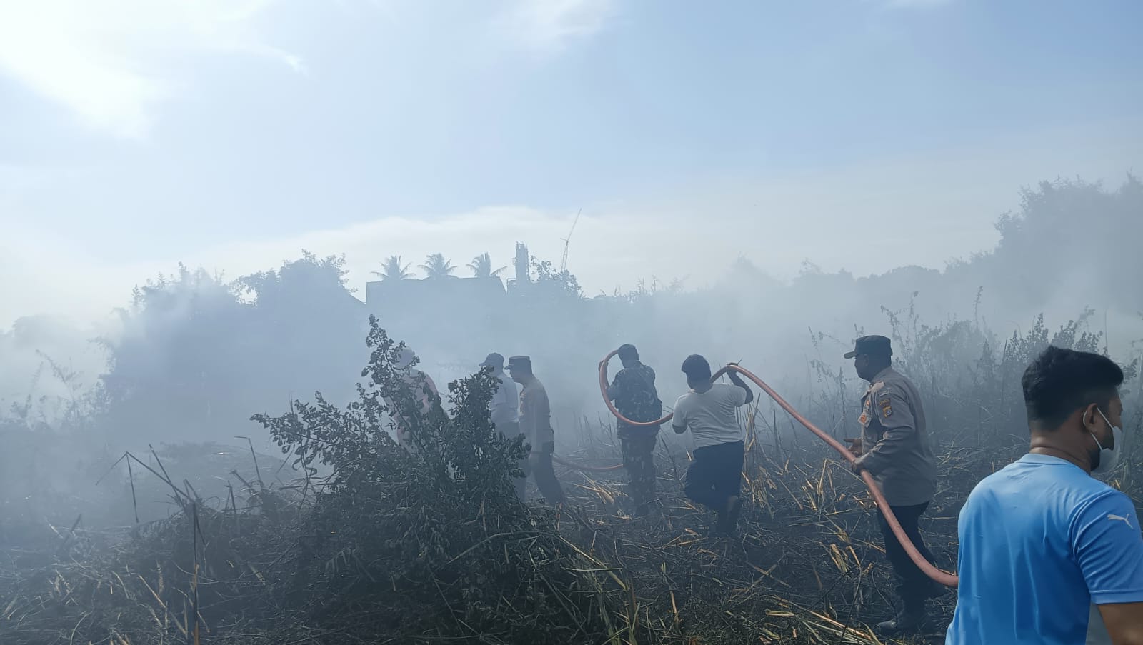 Kebakaran lahan ilalang di Gampong Blang Naleung Mameh, Kecamatan Muara Satu, Kota Lhokseumawe, Jum’at (28/7), personel Polsek Muara Satu membantu memadamkan api