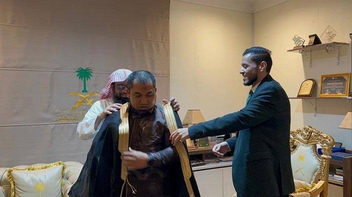 Kepala Atase Agama Kedubes Saudu Arabia, Syekh Ahmed Bin Essa Alhazmi memakaikan jubah Arab ke Pj Bupati Aceh Besar Muhammmad Iswanto sebagai penghormatan saat berkunjung di Kantor Atase Agama KBSA, Jakarta, Selasa (25/7/2023)