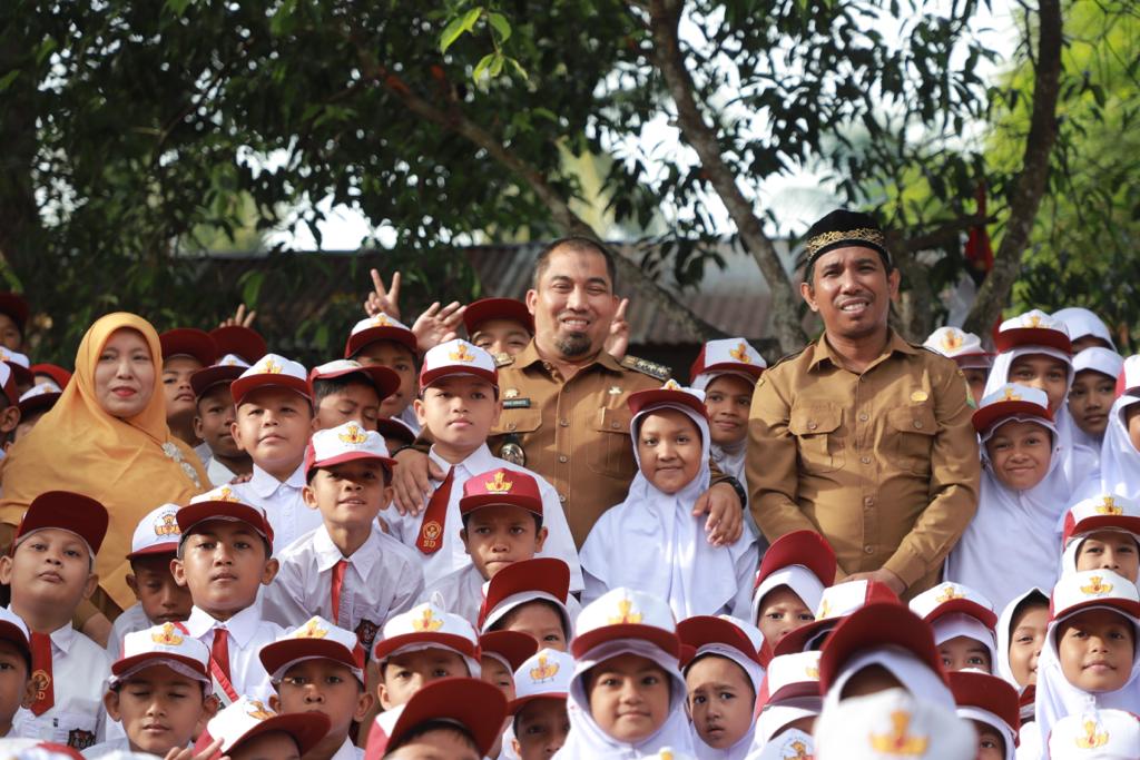 Pj Bupati Aceh Besar Muhammad Iswanto dan Kadisdikbud Aceh Besar Agus Jumaidi foto bersama dengan guru serta murid SDN Cot Meuraja saat kunjungan Program Saweu Sikula, di Cot Karieng, Kecamatan Blang Bintang, Senin (7/8). FOTO/PROKOPIM PEMKAB ACEH BESAR