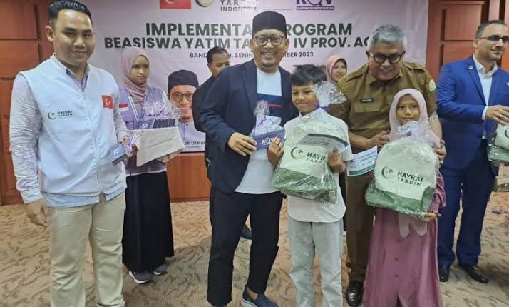 Sekda Aceh Bustami Hamzah didampingi Founder Rumah Quran Violet (RQV) Indonesia Azmi Fajri Usman menyerahkan beasiswa yatim kepada seratusan lebih anak binaan RQV di Aceh, Senin (4/12)