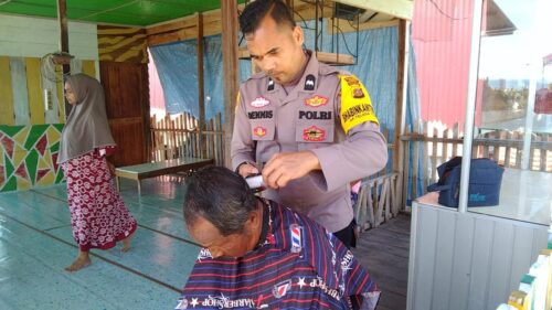 Anggota Bhabinkamtibmas Gampong Teulaga Tujoh Polsek Langsa Barat Polres Langsa, Aipda Dennis Siswanto memberikan layanan pangkas gratis di desa binaan
