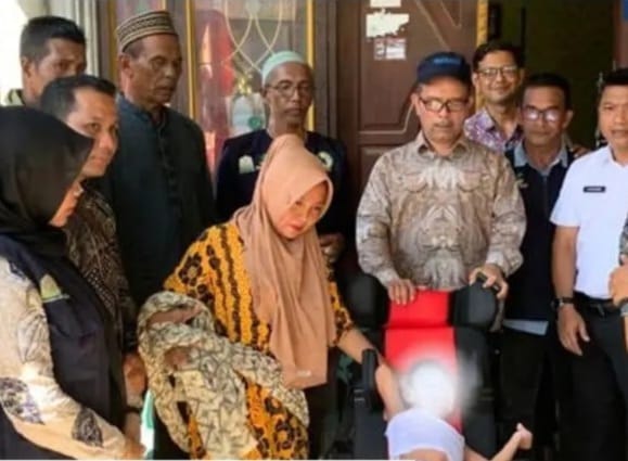Kadis Sosial Aceh Muslem Yacob menyerahkan kursi roda kepada bocah penderita Cerebral Palsy di Panteraja, Pidie Jaya, Kamis (1/2)