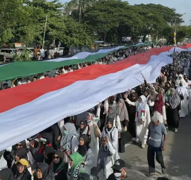 blbendera Indonesia dan Palestina sepanjang 100 meter yang dibentangkan di tengah barisan massa yang mengenakan atribut khas perjuangan Palestina. (Foto: Ist)