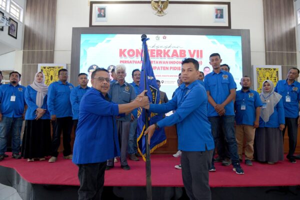 Ketua PWI Aceh, Nasir Nurdin menyerahkan pataka kepada Firman Zubir yang kembali terpilih sebagai Ketua PWI Pidie periode 2025-2028, dalam Konferkab VII, Sabtu (2/8). (Foto: Ist)